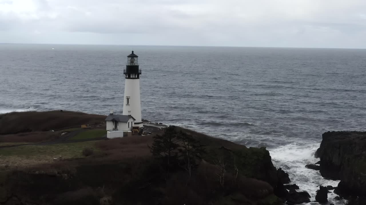 Yaquina Head Lighthouse, Pacific Ocean in Newport Oregon, aerial view pass by over waves