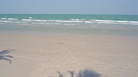 idyllic tropical beach, white sand, light waves and blue horizon, static slomo