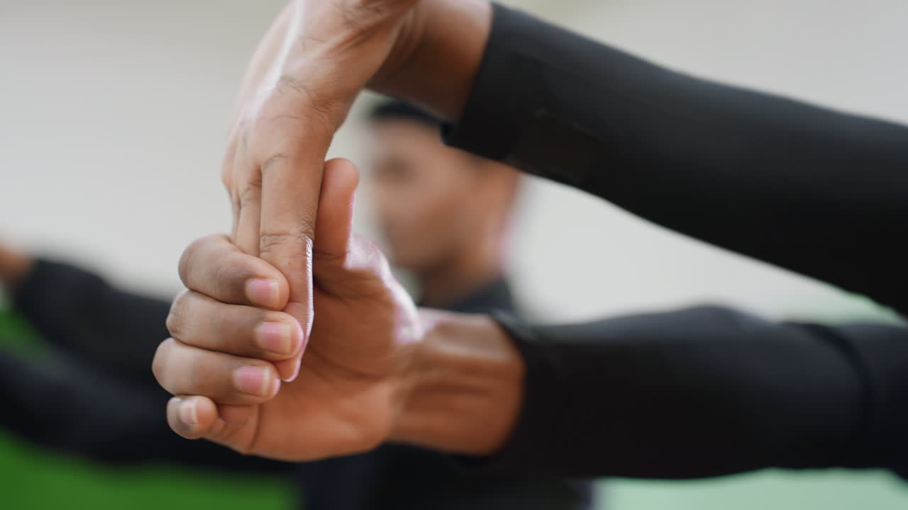 Close up of sportsmen stretching hands during indoor workout session focusing on wrist flexibility, control, concentration, and preparation for sports activity with blurred training background