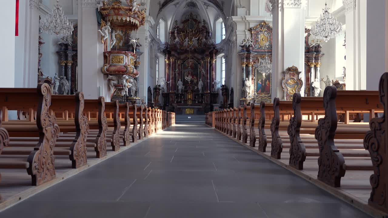 Clip video interni grandangolari che mostrano le panche di legno, la navata centrale e l'architettura barocca decorata del monastero benedettino di Einsiedeln