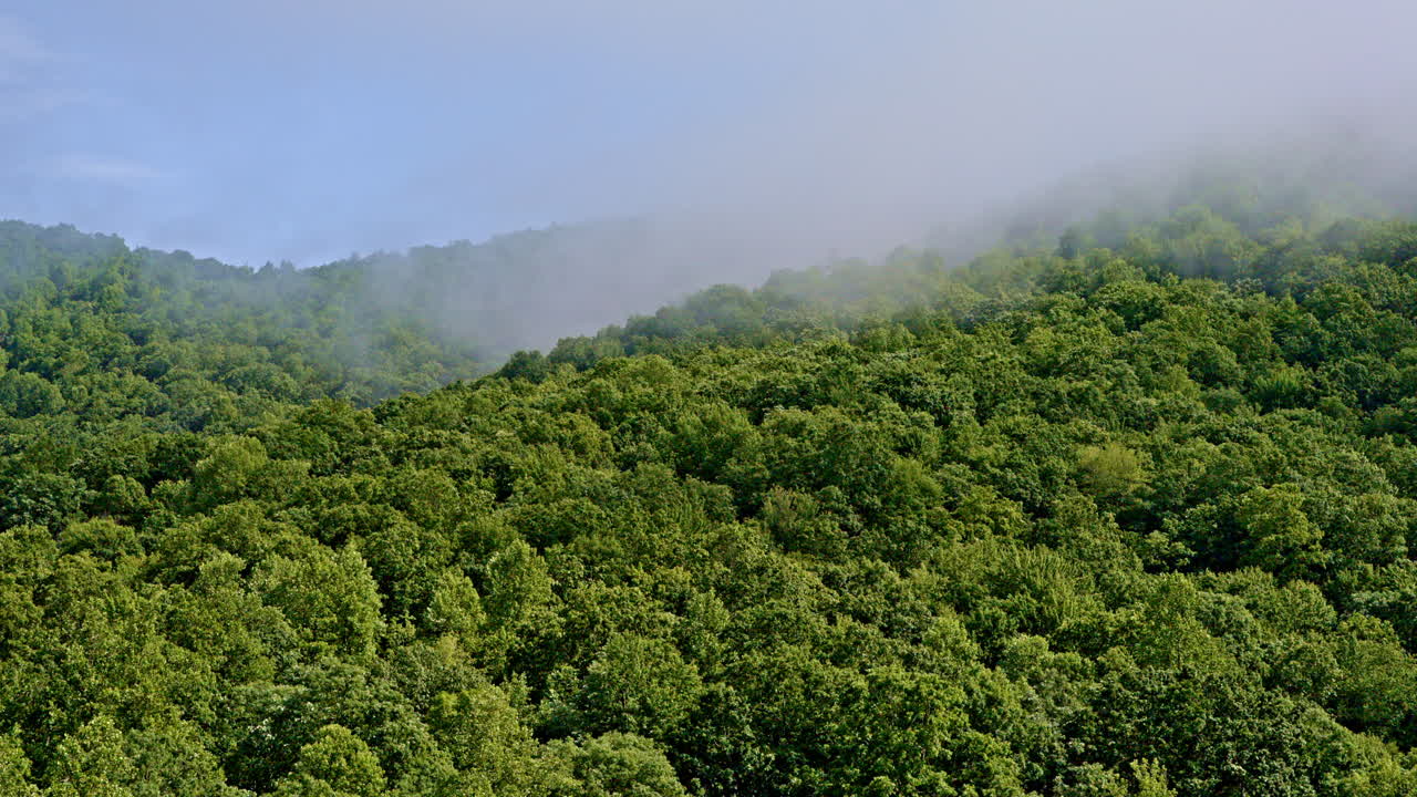 Drone camera floating into clouds settling on the mountains