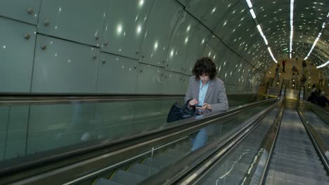 woman using smartphone on subway escalator