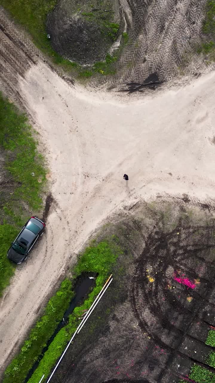 vista aérea de una intersección de carretera de tierra en tierras de cultivo con un coche y una persona