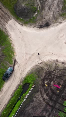 vista aérea de una intersección de carretera de tierra en tierras de cultivo con un coche y una persona