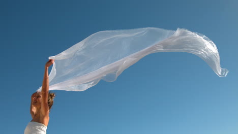 Carefree-blonde-holding-scarf-up-blowing-in-the-wind