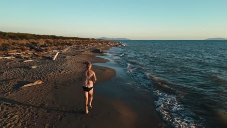 One-senior-man-running-jogging-at-a-sandy-beach-sea-at-sunset-doing-active-sport-fitness-training-and-staying-fit,-a-healthy-body,-muscles-and-endurance