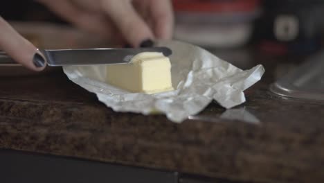 cortar mantequilla con un cuchillo de pan inoxidable con un fondo borroso