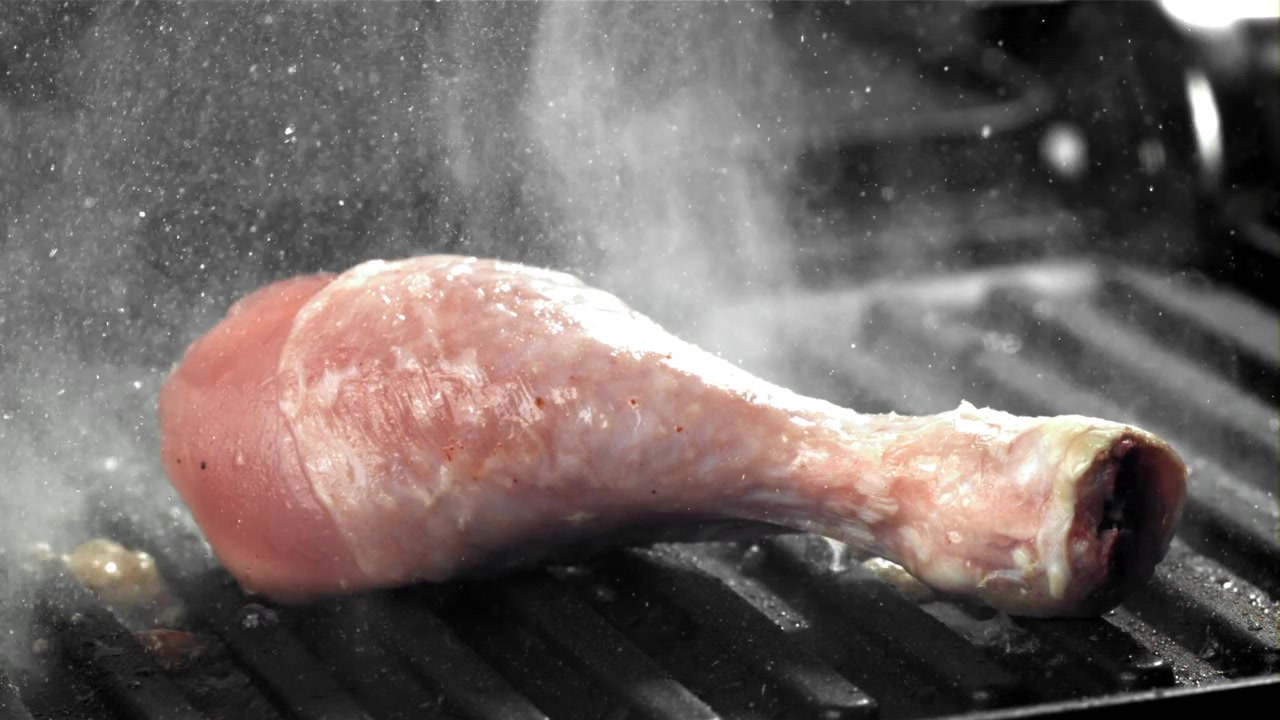 Rå kyllingklubbe freser på en varm grill