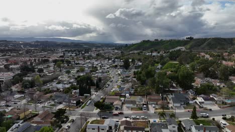Suburban-neighborhood-on-a-cloudy-dramatic-afternoon-with-sky-covered-in-clouds,-establishing-aerial-view