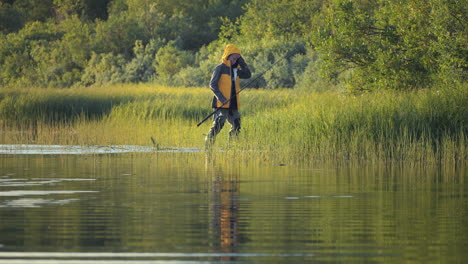 young fisherman walking in wet reed coastline in sweden