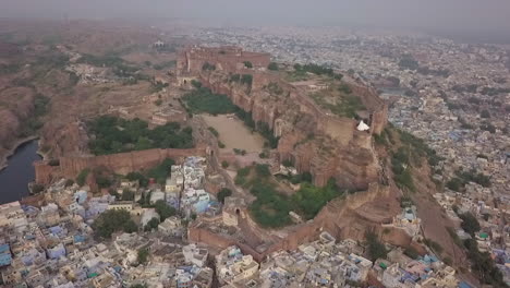 Aerial:-Massive-ancient-Mehrangarh-Fort-high-above-Jodhpur,-India