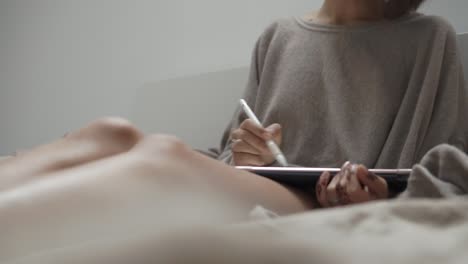 woman drawing on a tablet in bed