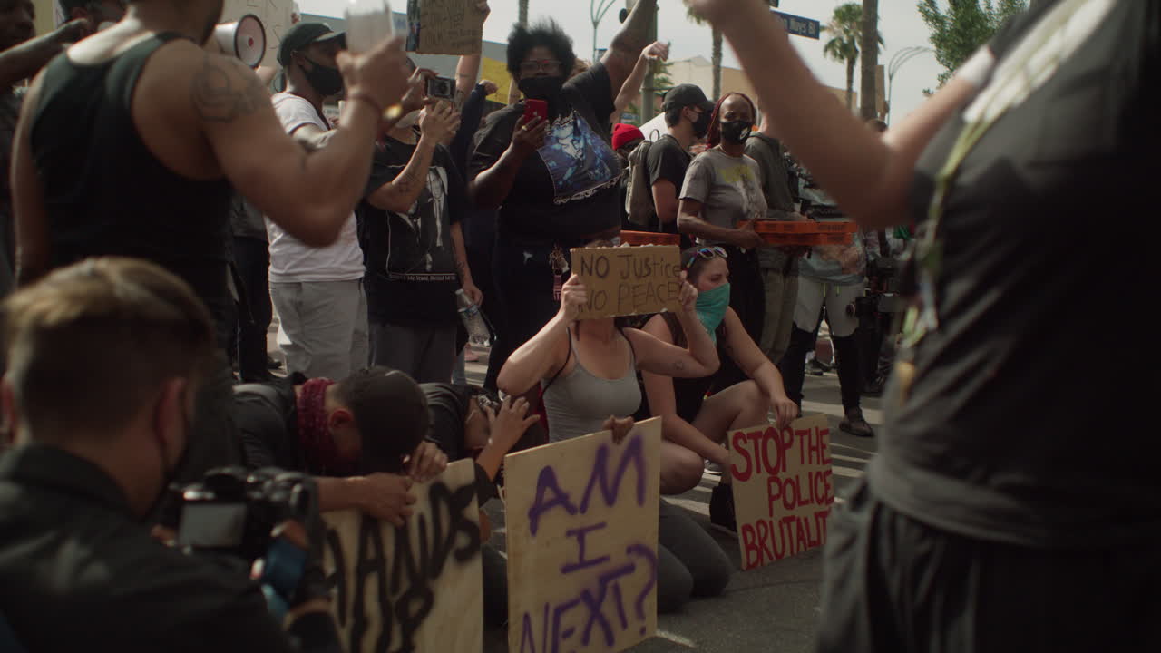 Group of protestors holding up multiple signs during a protest in front of police at the town hall