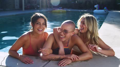 Portrait-Of-Three-Female-Friends-Outdoors-Relaxing-In-Swimming-Pool-And-Enjoying-Summer-Pool-Party