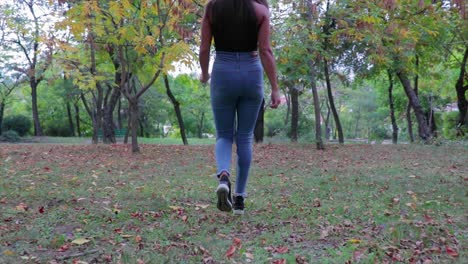 hermosa chica caminando por un parque verde tiro de seguimiento de ángulo bajo