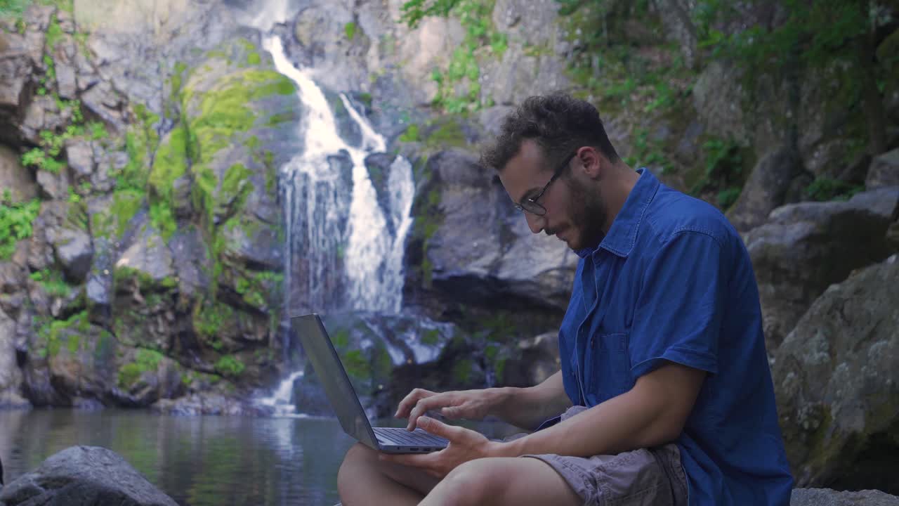 hombre de negocios trabajando con una computadora portátil en la cascada.