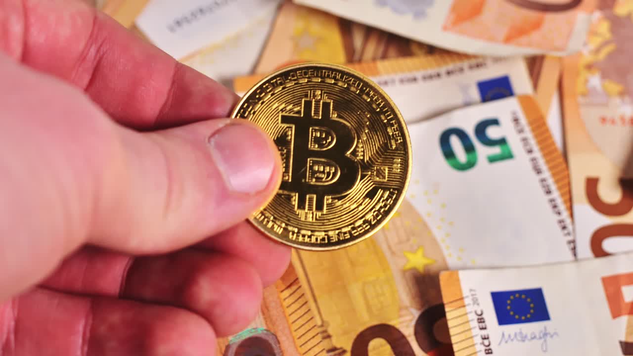 Person holding a Bitcoin coin above euro banknotes, symbolizing digital finance