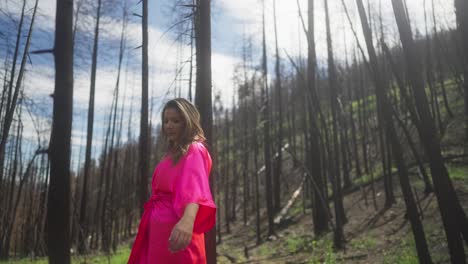 mujer en cámara lenta en túnica rosa caminando por el bosque