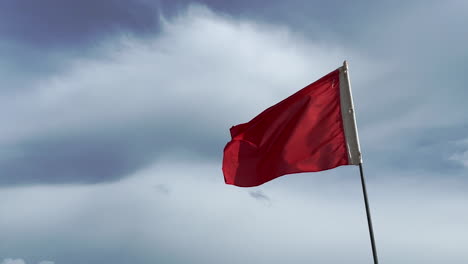 Closeup-shot-of-Red-flag-with-sky-in-background-Goa-India-4K