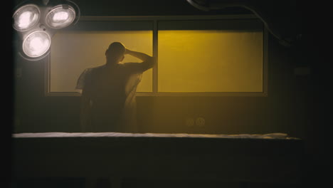 a bald man looks through the yellow glass in the operation room