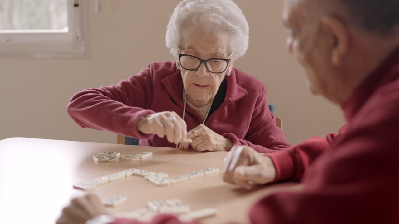 Senior people playing dominoes patiently in a nursing home