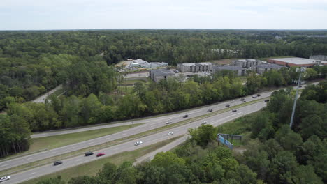 Aerial-over-highway,-surrounded-by-dense-forest,-lush-green-trees