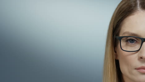 close up of the half face of the serious beautiful woman physician in glasses looking straight to the camera