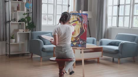 talented female artist energetically, enthusiastically using paint brush she creates modern masterpiece of the oil painting. creative studio with canvas