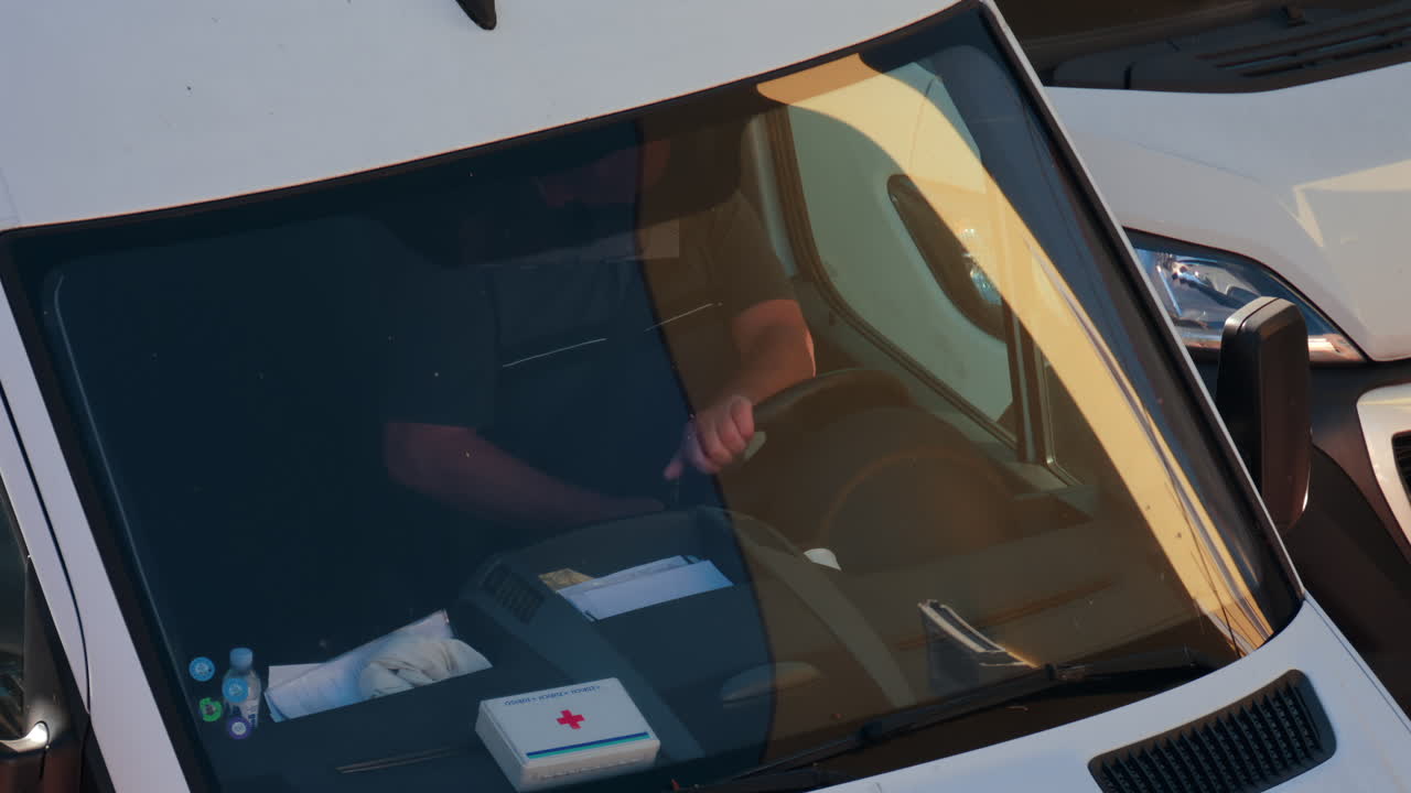 Chisinau, Moldova - September 28, 2025: A man siting behind the wheel of a white van, viewed through the windshield