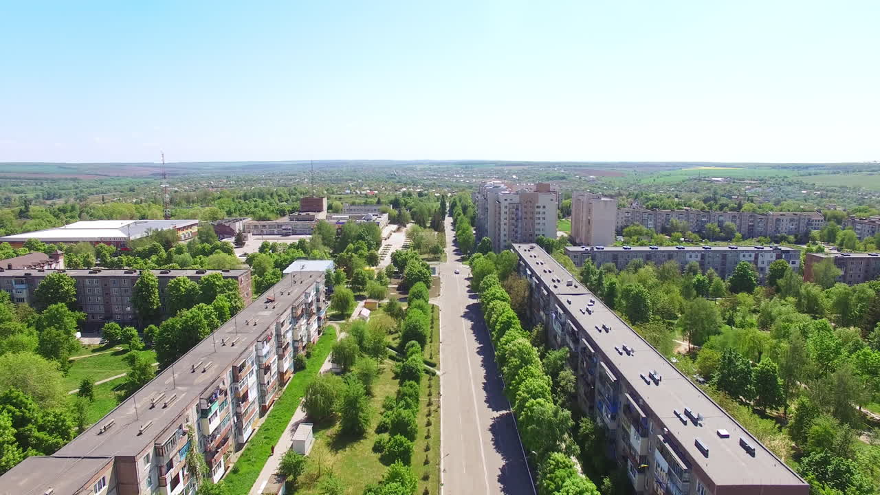 Flight over the plain usual city on beautiful sunny summer day. Residential areas with lots of greenery and empty streets. Top view.