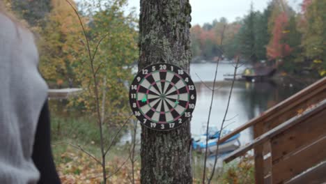 white woman throws a dart at a dart board and misses