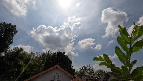 time lapse of the movement of white clouds in the blue sky, foreground green leaves