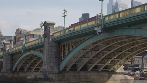 view from boat on river thames going under southwark bridge showing buildings on city of london financial skyline