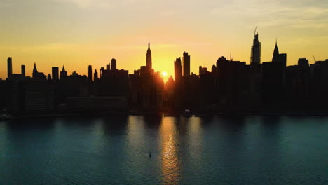 Skyscrapers'-Silhouette,-aerial-sliding-shoot-of-New-York-City-at-golden-hour,-with-the-Sun-crossing-the-city-from-one-side-to-another