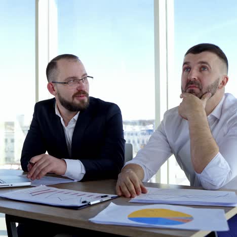 businessmen brainstorm new ideas. thoughtful partners sitting at the table and discus about the plan of their company in office. portraits of two entrepreneurs