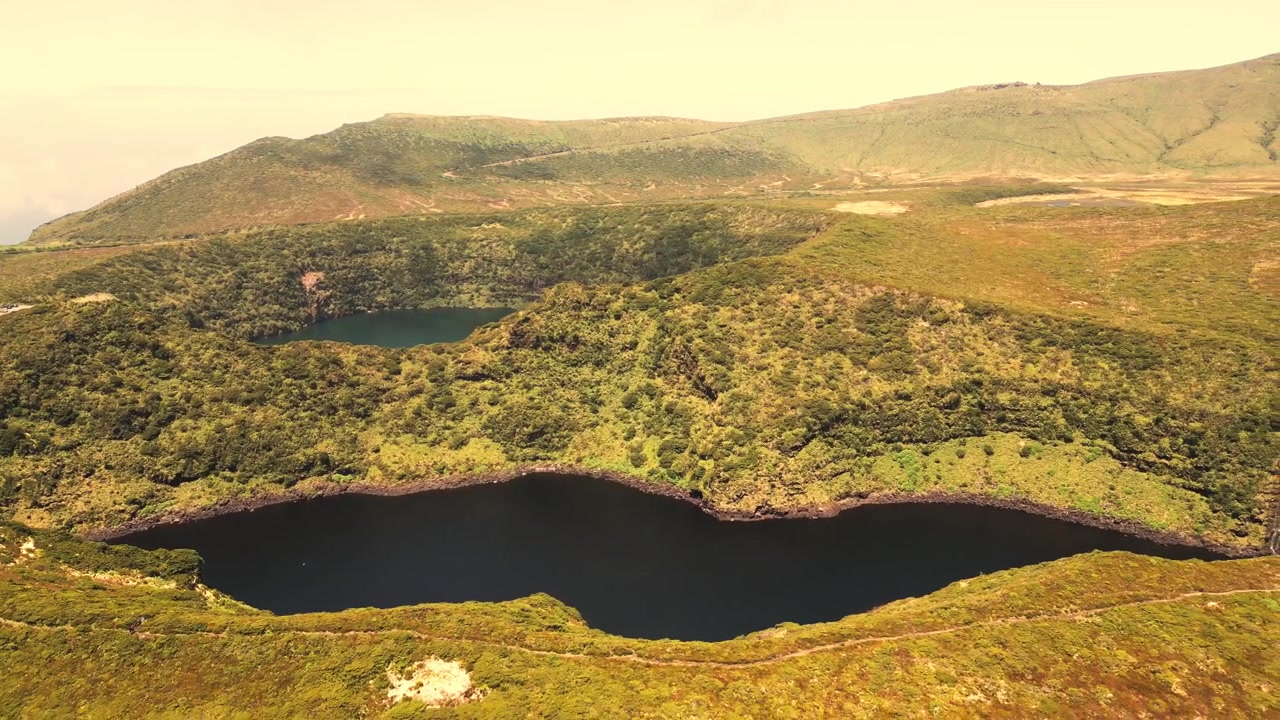 Vista aérea de lagos de cratera vulcânica cercados por colinas verdes exuberantes na Ilha das Flores