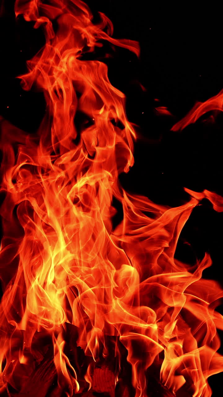 Fire flame on isolated black background. Fire sparks glowing with warm. Vertical video