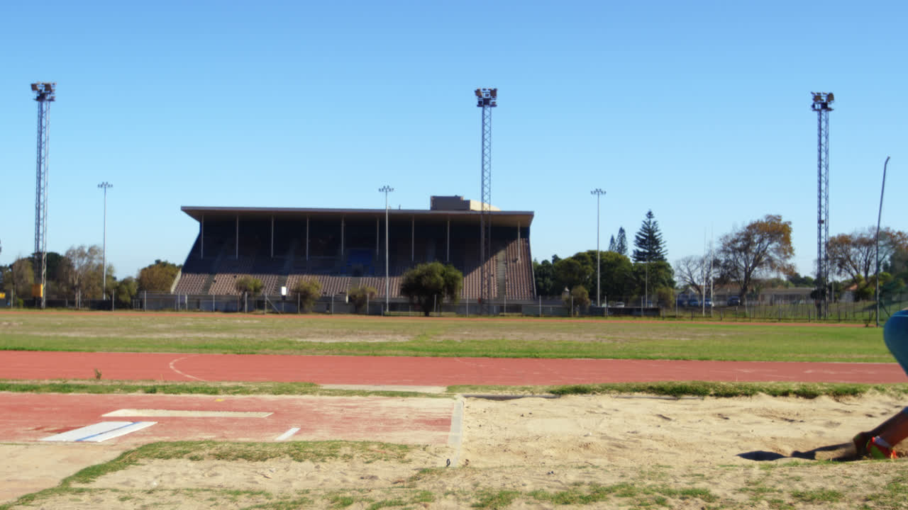 Side view of Caucasian female athlete practicing long jump at sports venue 4k
