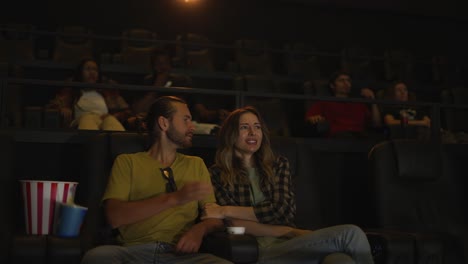 beautiful girl looking scary while watching film and snuggling to her boyfriend sitting next to her