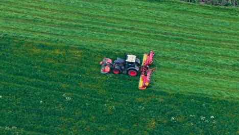 agricultural mower cutting grass on a farm field - drone shot