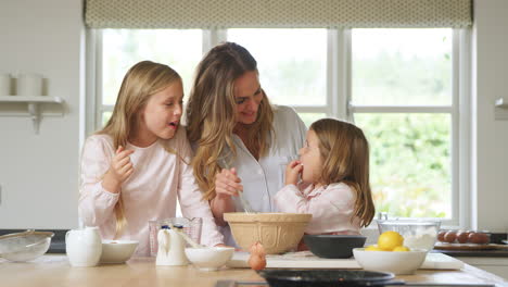 Mutter-Und-Zwei-Töchter-Im-Schlafanzug-Backen-Gemeinsam-In-Der-Küche-Zu-Hause