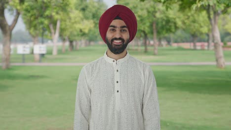 happy sikh indian man smiling to the camera in park