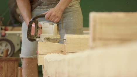 caucasian craftsman uses electric chainsaw to carve wood log