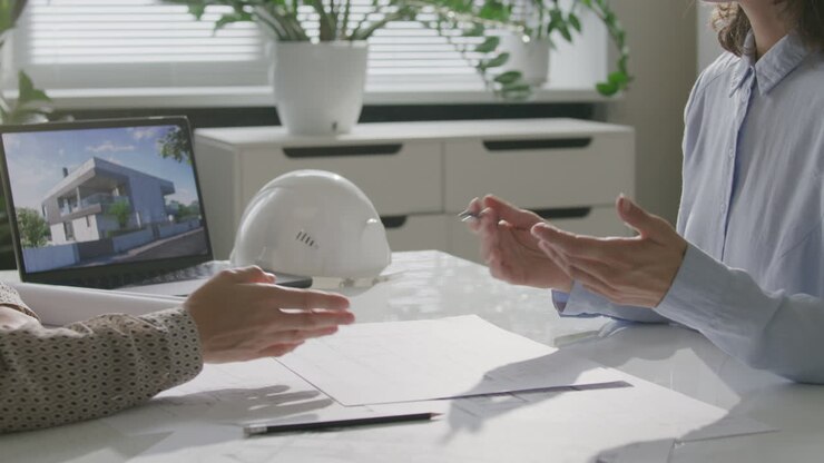 Two Female Architects Discussing Building Floor Plans during Meeting