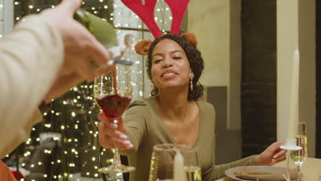 man pouring red wine on her friend's glass