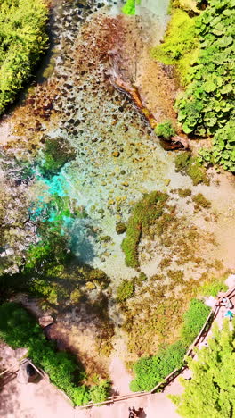 mountainous river flowing by the rocky area. tourists walk by the picturesque paths in albania. vertical video.