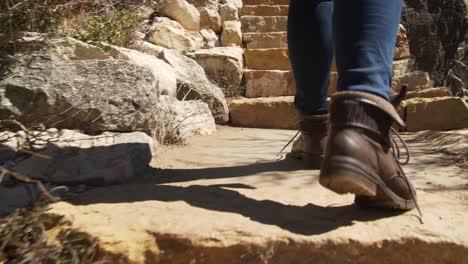 una mujer sube un conjunto de escalones de piedra que conducen fuera de walnut canyon, az