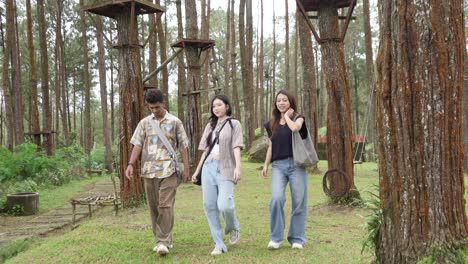 young asian friends walking on forest footpath in nature