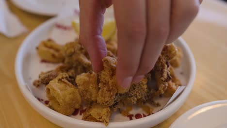 hand picking fried calamari from a plate