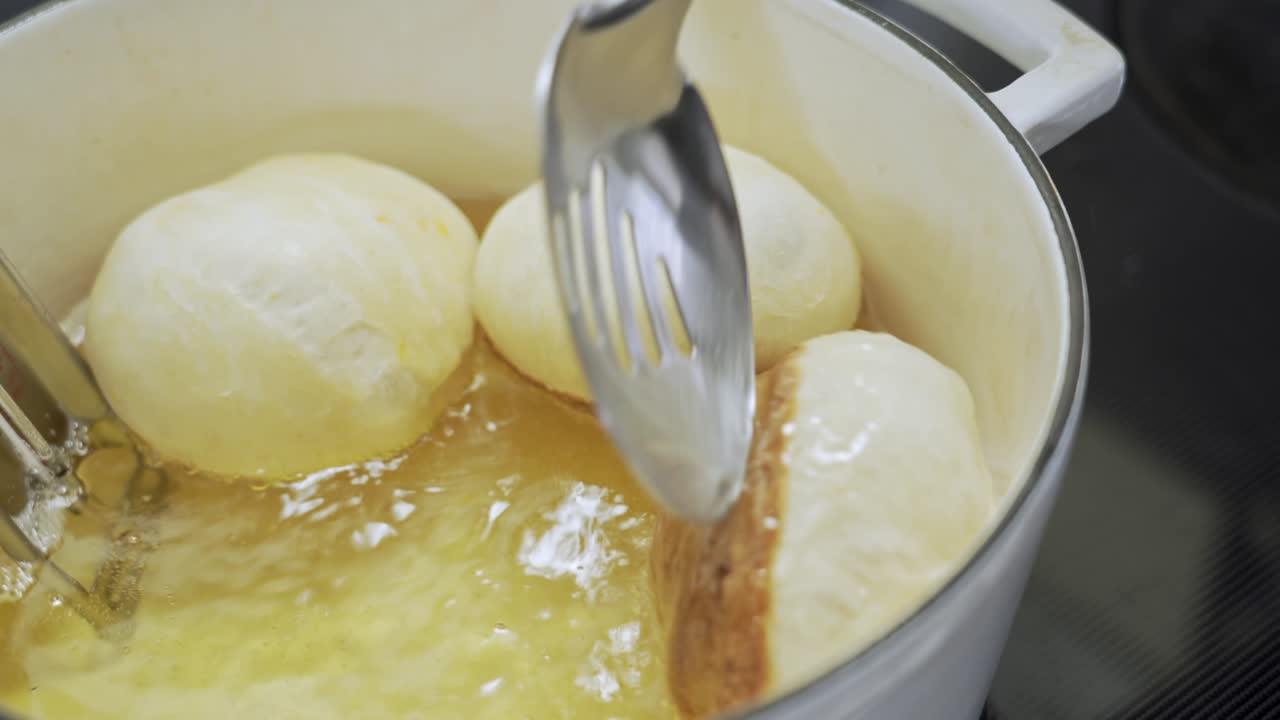 홈메이드 도넛을 튀기고 흰색 팬에 뜨거운 기름에 넣고 뒤집고 닫습니다.